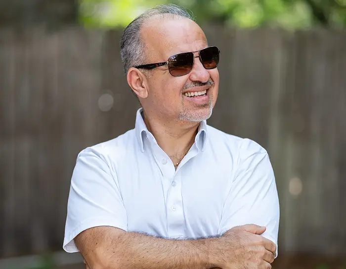 A man with sunglasses on his head and arms crossed.