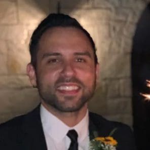 A man in a suit and tie smiling for the camera.