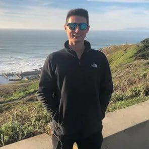 A man standing on top of a hill near the ocean.