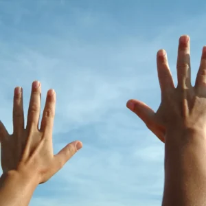 Two hands reaching up into the air in a sky background