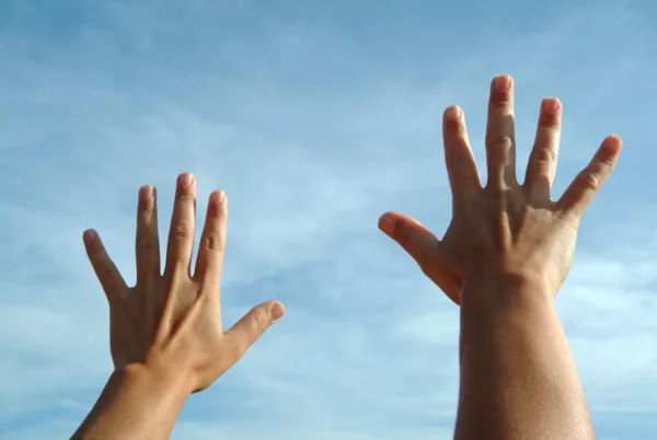 Two hands reaching up into the air in a sky background