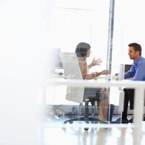 Two people sitting at a table in front of laptops.