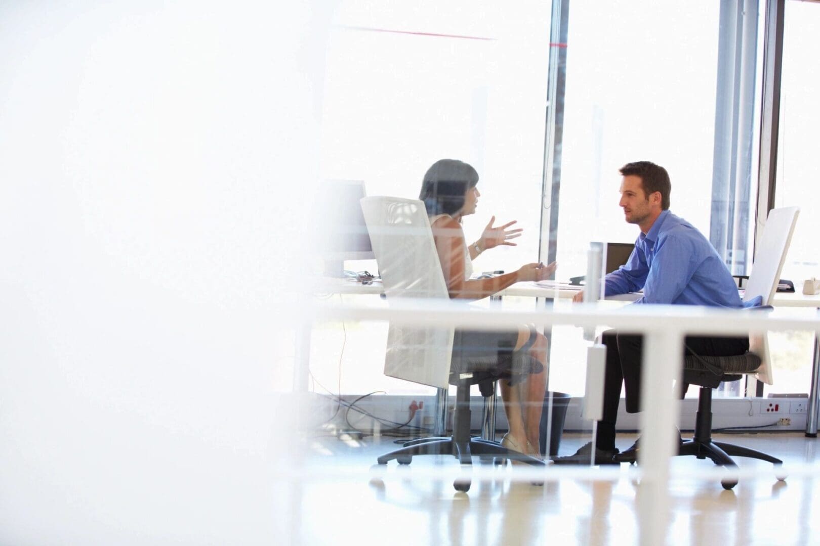 Two people sitting at a table in front of laptops.