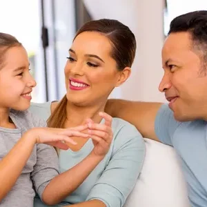 A woman and two men sitting on the couch with a girl.