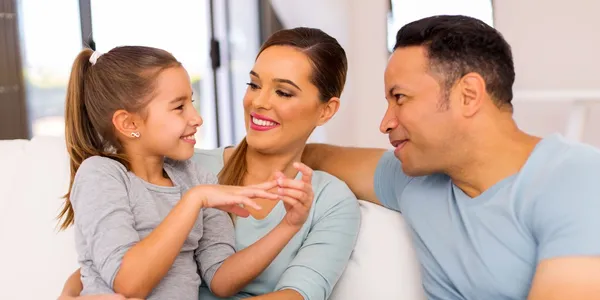 A woman and two men sitting on the couch with a girl.