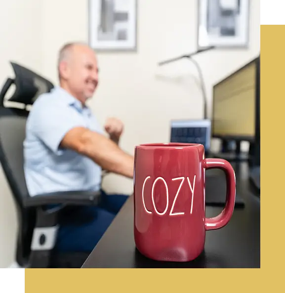 A man sitting at his desk with a coffee mug.