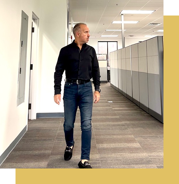 A man walking down the hallway of an office building.